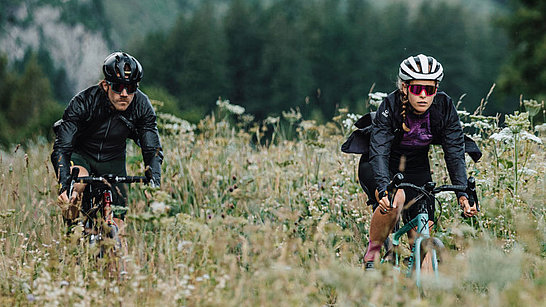 Zwei Radfahrer mit Sportbrillen auf einer Bergwiese