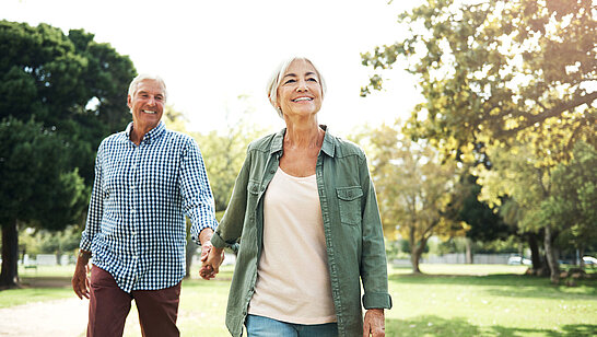 Eine ältere Dame und Herr gehen Hand in Hand spazieren