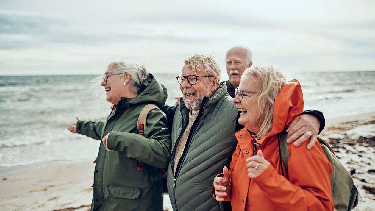 Eine Gruppe älterer Personen am Strand mit Windjacken