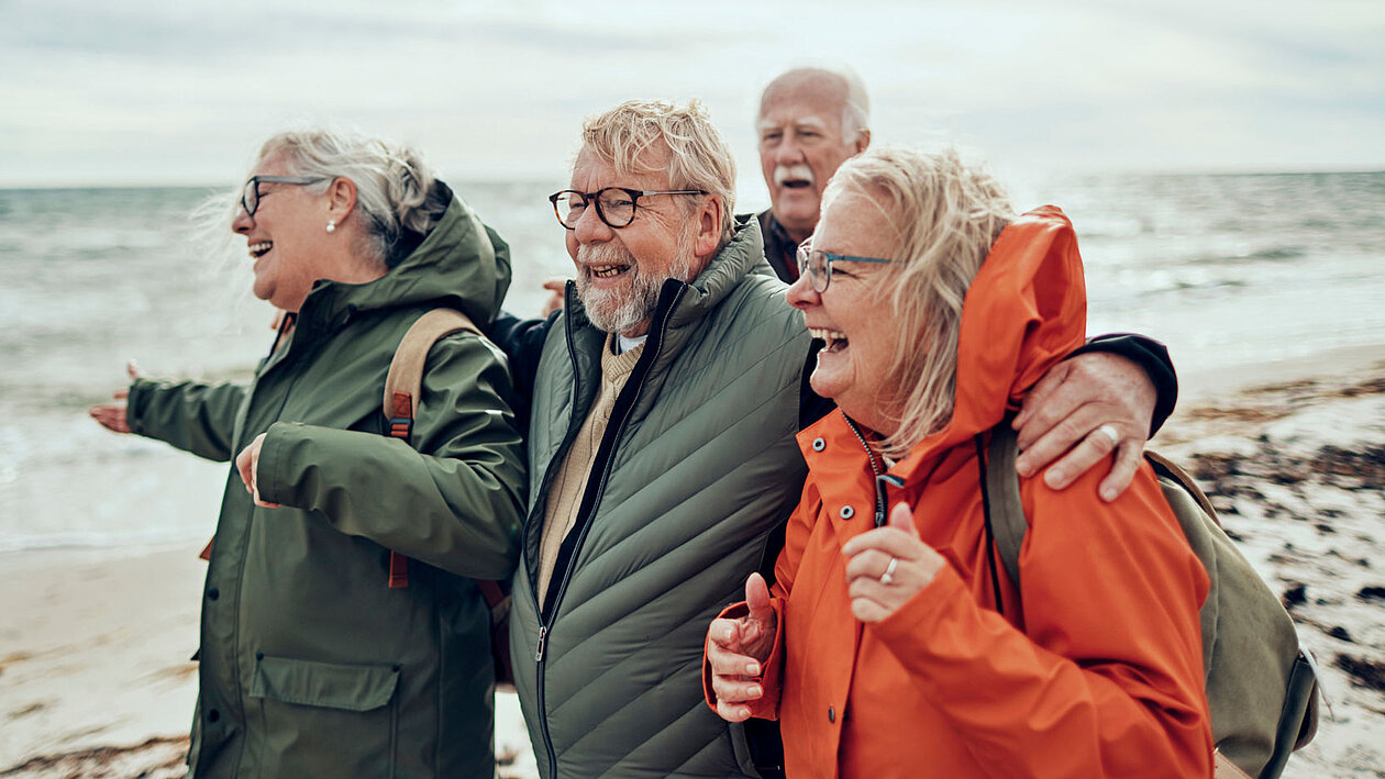 Eine Gruppe älterer Personen am Strand mit Windjacken