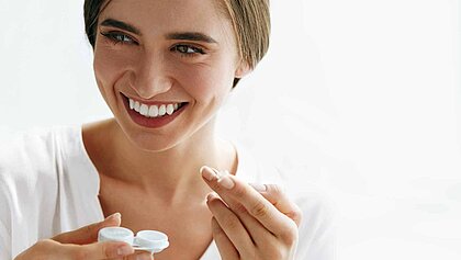 Eine Frau mit Kontaktlinsenbehälter in der Hand