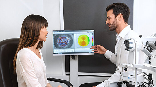 Ein Augenoptiker erklärt einer Dame Aufnahmen eines Sehtests 