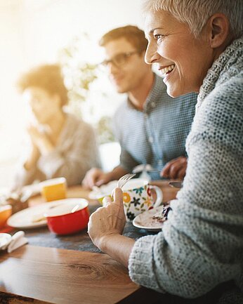 Eine Gruppe Meschen sitzt an einem Tisch und unterhält sich gut