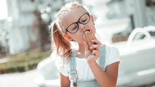Ein Mädchen mit Brille isst ein Eis