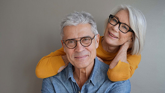 Ein älterer Herr mit Brille und eine ältere Dame mit Brille posieren für ein Foto