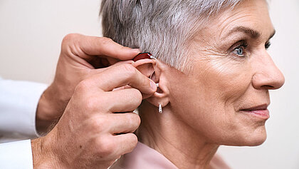 Einer älteren Dame wird ein Hörgerät eingesetzt