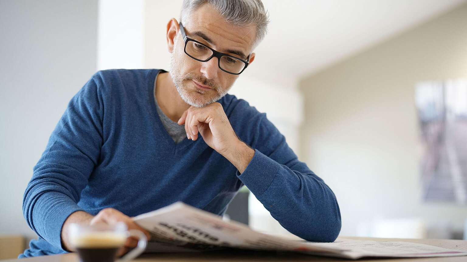 Herr mit Brille liest Zeitung